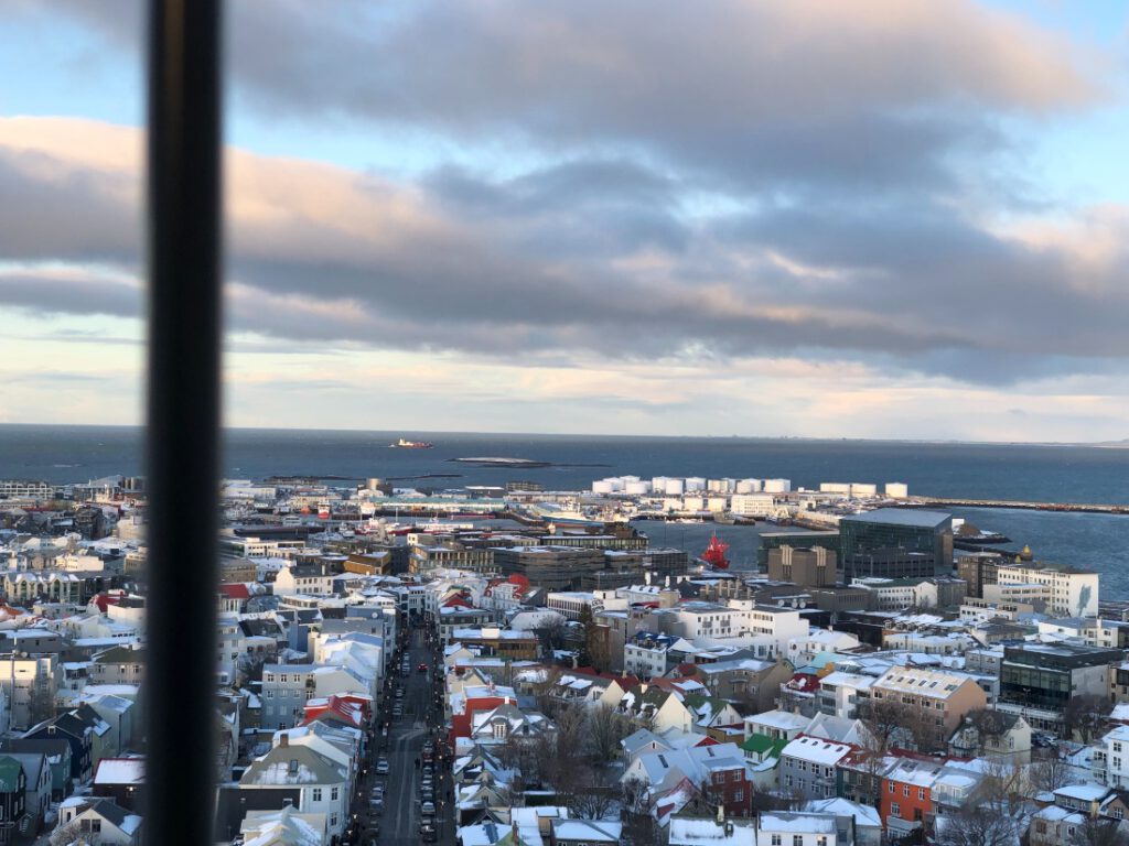 Blick vom Turm der Hallgrimskirkja auf die Stadt und den Hafen von Reykjavik. Rechts neben dem roten Schiff die Konzerthalle Harpa