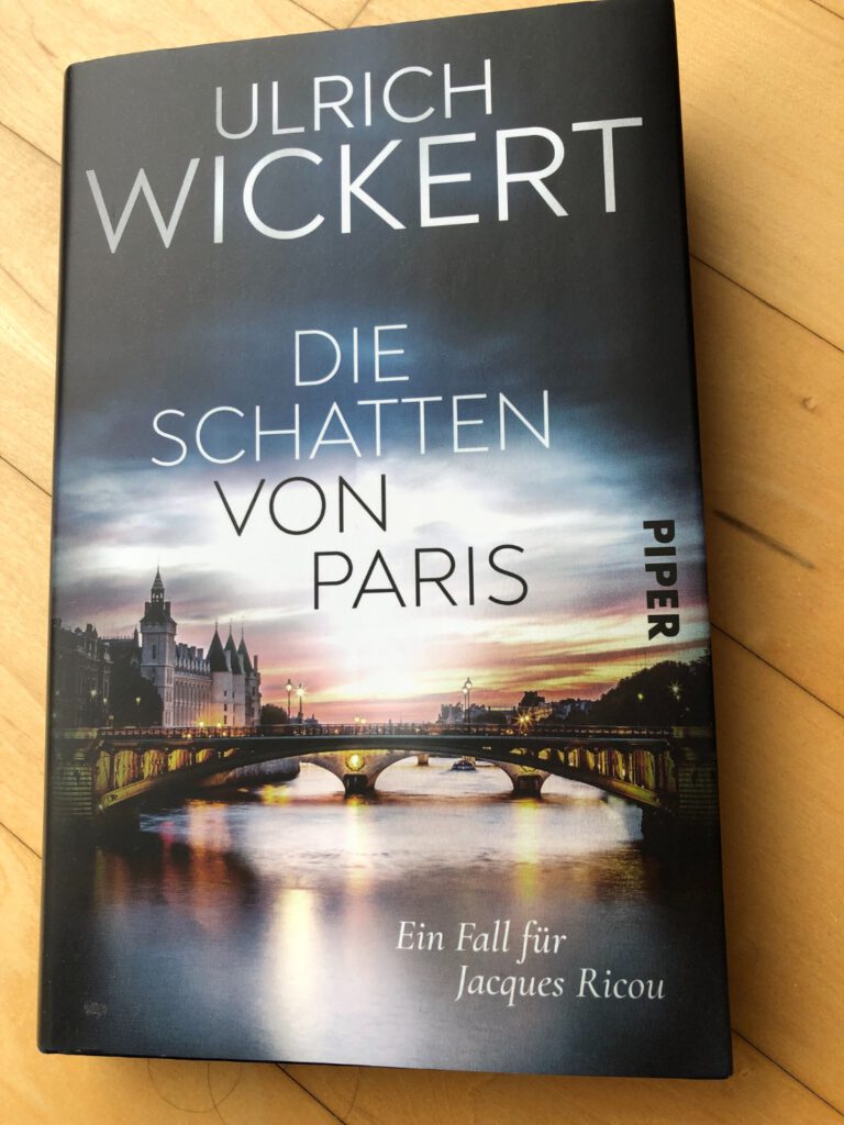 Lektüre privat: Ulrich Wickert - Die Schatten von Paris - Ein Fall für Jacques Ricou Auf dem Buch Cover ist eine beleuchtete Seine-Brücke mit beiden Ufern zu sehen. Das Abendrot und die Gebäude spiegeln sich im Fluss